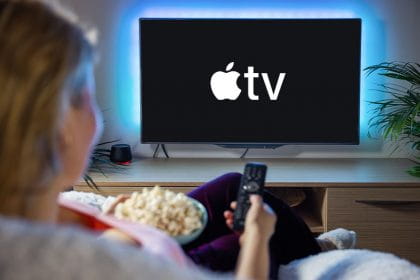 Frau ist von hinten auf der Couch zu sehen, hat Popcorn neben sich und schaut Apple TV