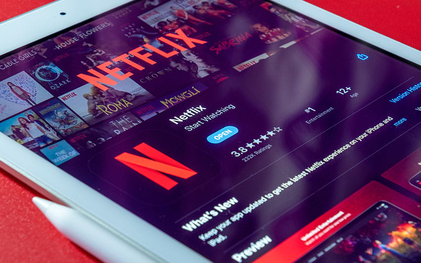 Frau tippt auf Tablet und hat Netflix auf dem Browser