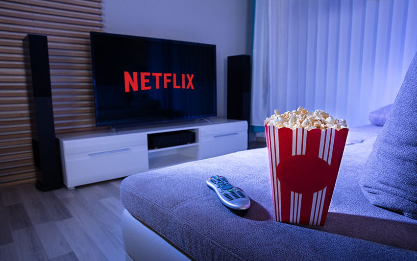 Zu sehen sind ein Bildschirm, der Netflix zeigt und eine Schüssel Popcorn